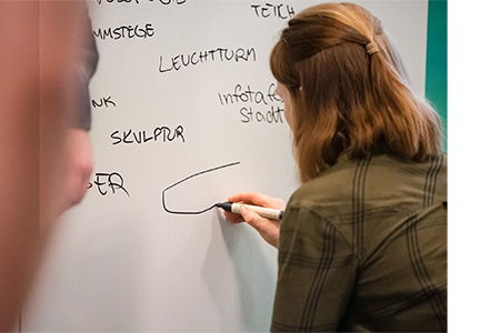 Eine Teilnehmerin zeichnet an ein Whiteboard